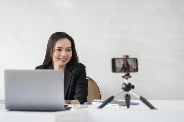 Erwachsene asiatische Hochschullehrerin, die online per Videokonferenz für Studenten zu Hause unterrichtet