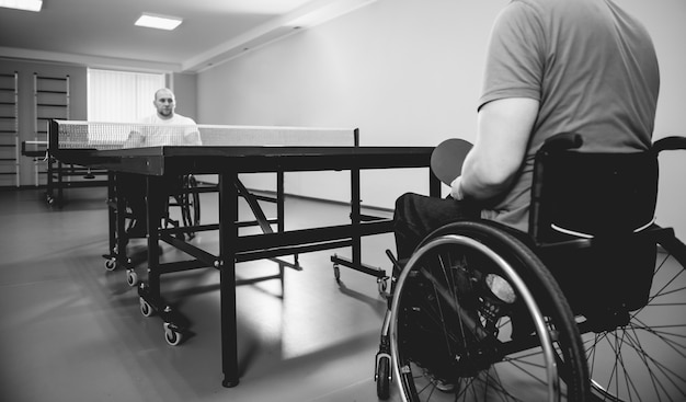 Erwachsene behinderte Männer in einem Rollstuhl, der Tischtennis spielt
