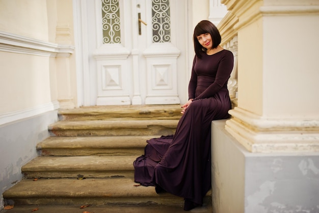 Erwachsene brünette Frau im violetten Kleid Hintergrund altes Vintage-Haus mit Treppe