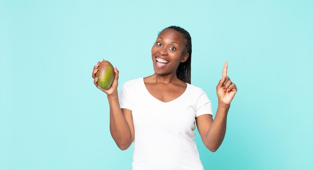 Erwachsene Frau des Schwarzafrikaners, die eine Mangofrucht hält