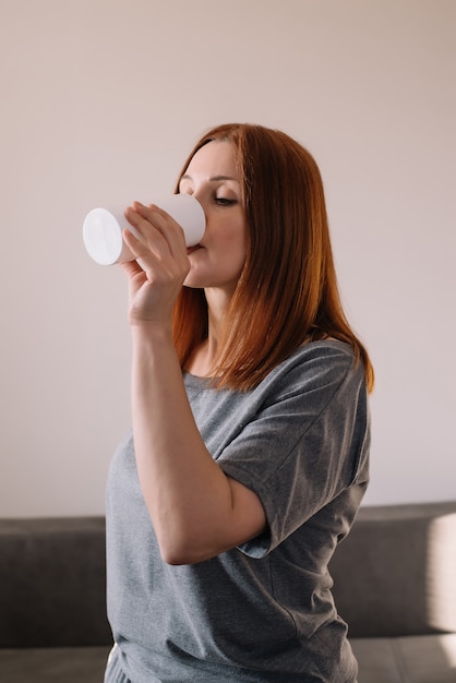 Erwachsene Frau, die ein frisches Glas Wasser zu Hause trinkt.