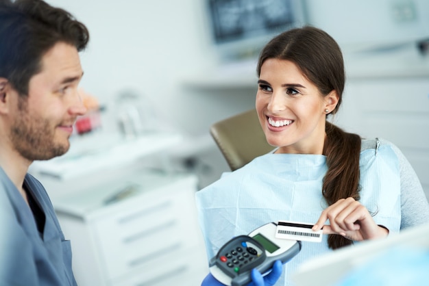 Erwachsene Frau, die für den Besuch in der Zahnarztpraxis bezahlt