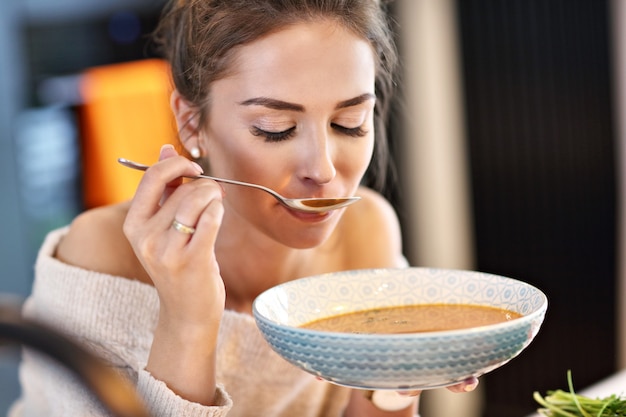 Foto erwachsene frau, die in der küche kürbissuppe schmeckt