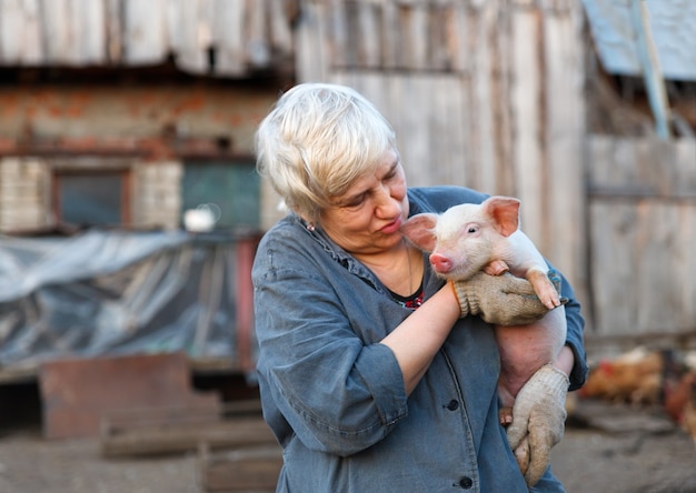 Erwachsene Frau, die liebevoll ein kleines Schwein hält