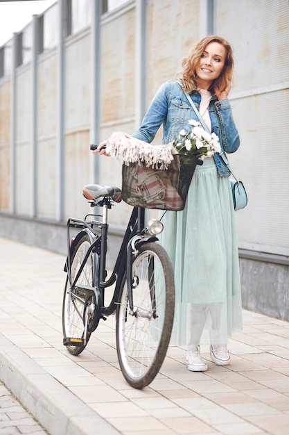 Erwachsene Frau, die mit Stadtfahrrad geht