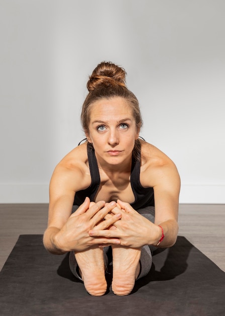 Foto erwachsene frau, die yoga zu hause macht