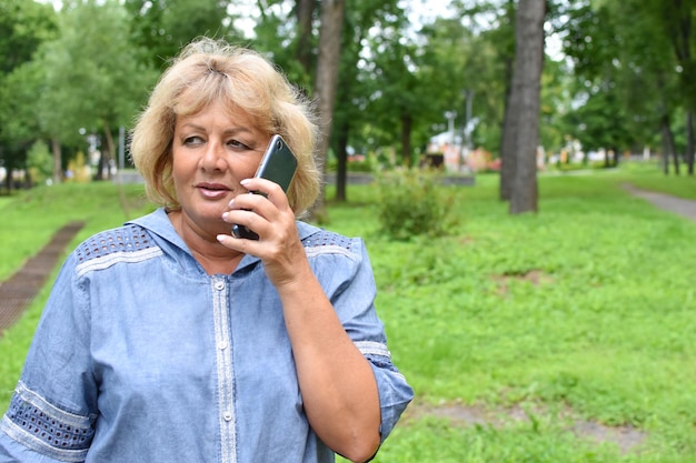 Erwachsene Frau im Park telefoniert Frau im Alter kommuniziert online