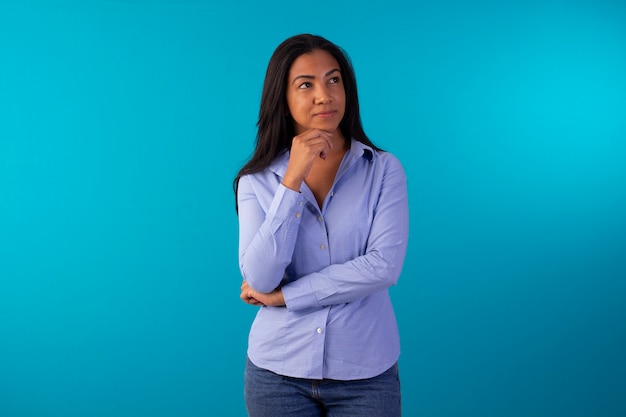 Erwachsene Frau in formeller Kleidung, blaues Hemd und Jeans im Studiofoto mit blauem Hintergrund tragend.