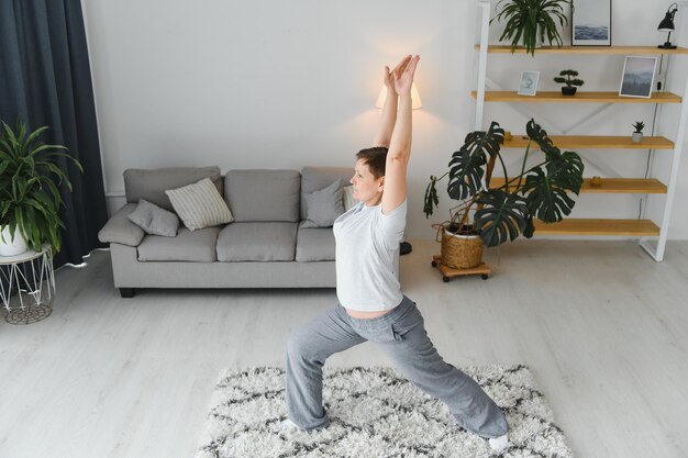 Erwachsene Frau macht Fitnessübungen zu Hause Ältere Frau macht Dehnübungen Reife Frau macht Yoga-Posen