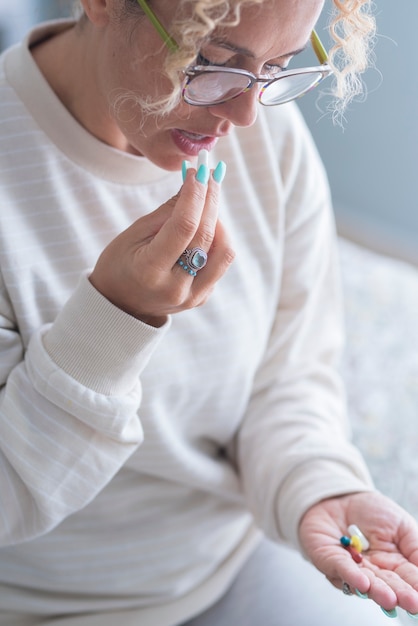 Erwachsene Frau mittleren Alters, die zu Hause Tabletten einnimmt und allein auf dem Bett sitzt bed