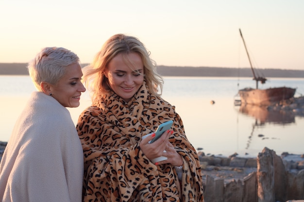 Erwachsene Frauen Homosexuelles Paar nutzen ein Smartphone am Strand