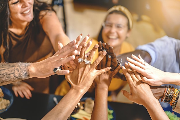 Erwachsene Freunde in der Gruppe, die um den Esstisch herum Highfives sitzen, feiern alle zusammen die Freundschaft und vereinen sich zusammen Konzept des Lebensstils vertrauen Einheit Zusammengehörigkeit konzentrieren sich auf Hände