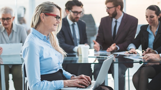 Erwachsene Geschäftsfrau mit Laptop, der vor Büro Schreibtisch sitzt. Menschen und Technologie