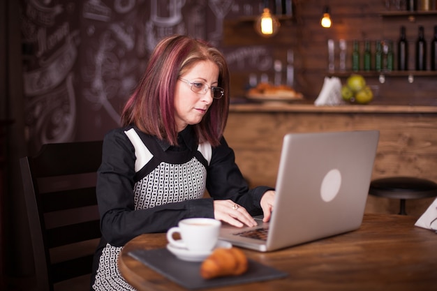 Erwachsene Geschäftsleute mit Brille arbeiten am Laptop im Vintage-Café?