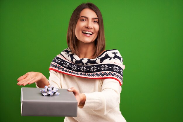 Erwachsene glückliche Frau mit Weihnachtsgeschenk über grünem Hintergrund