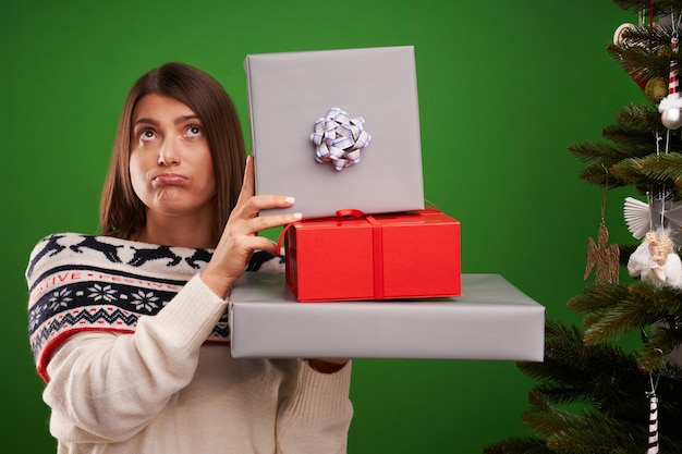 Erwachsene glückliche Frau mit Weihnachtsgeschenk über grünem Hintergrund