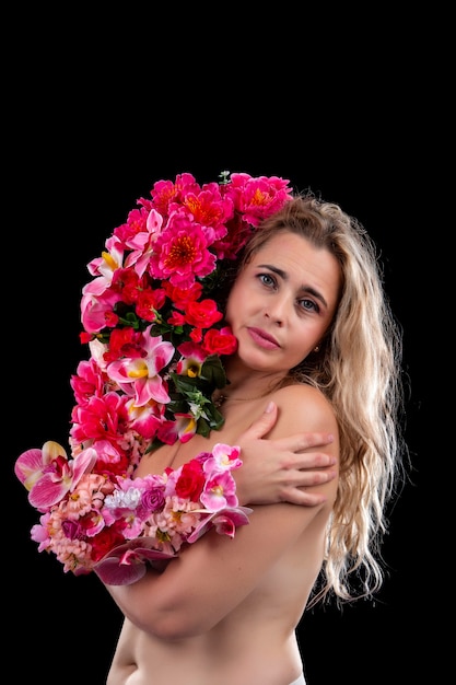 Erwachsene junge Frau mit Arm bedeckt in Blumen, die Mutter Erde Konzept über einem Schwarz symbolisieren.