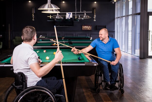 Erwachsene Männer mit Behinderungen im Rollstuhl spielen im Club Billard