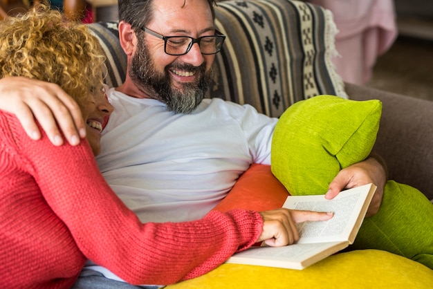 Erwachsene Menschen kaukasischer Mann und Frau paar zu Hause, die zusammen ein Buch lesen und Zeit und Leben auf der Couch teilen