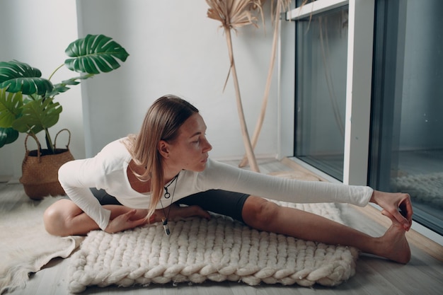 Erwachsene reife Frau, die Yoga zu Hause Wohnzimmer mit Online-Tutorials auf Laptop macht