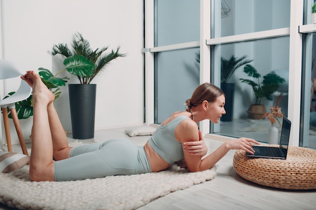 Erwachsene reife Frau, die Yoga zu Hause Wohnzimmer mit Online-Tutorials auf Laptop macht