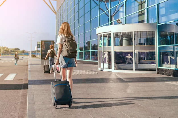 Erwachsene Touristin mit Handgepäckkoffer und Rucksack geht zum Flughafen für die Reise. Frau bereit, den Flug zu besteigen. Erstaunliche Sommerabenteuer