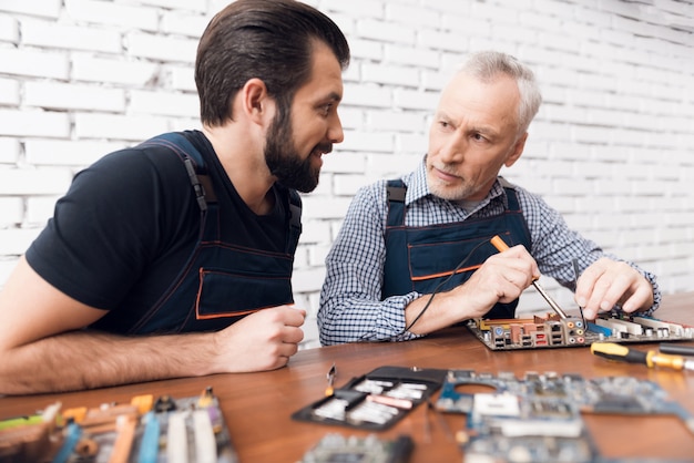 Erwachsene und junge Männer reparieren Teile vom Computer zusammen.