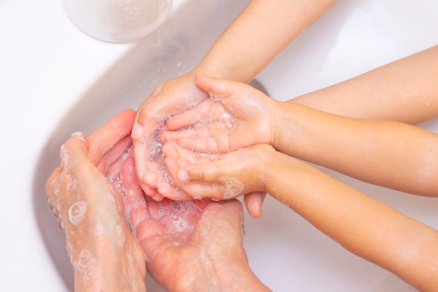 Foto erwachsene und kinder waschen sich die hände. hände in schaum aus antibakterieller seife. schutz vor bakterien, coronavirus. hand hygiene. hände waschen mit wasser. viele hände