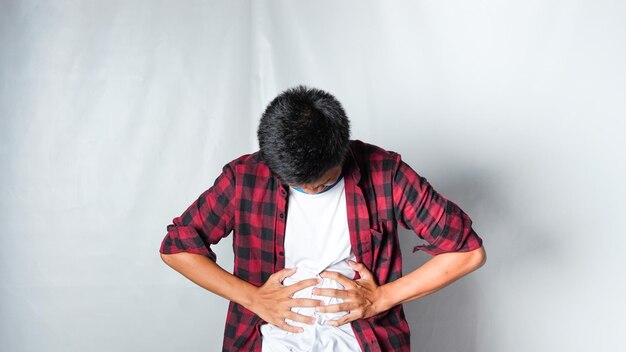 Foto erwachsener asiatischer mann mit rotem flanell-t-shirt magenkrankheit isoliert auf weißem hintergrund