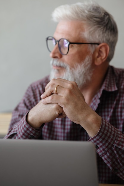 Erwachsener Geschäftsmann mit grauen Haaren arbeitet an einem Laptop in seiner Bürokarriere Finanzen und Marketing