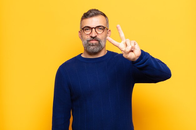 Foto erwachsener gutaussehender mann, der lächelt und freundlich aussieht, nummer zwei oder sekunde mit der hand vorwärts zeigend, herunterzählend