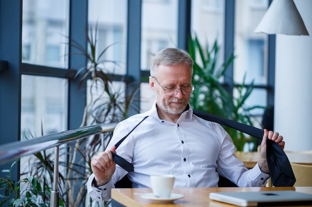 Erwachsener männlicher Manager-Geschäftsmann hat erfolgreich gearbeitet und trinkt am Ende des Tages Kaffee ohne Jacke