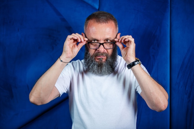 Erwachsener männlicher Mentor, Direktor, Geschäftsmann in Brille und Anzug, der Dokumente studiert, während er am Tisch sitzt. Konzept des Arbeitstages