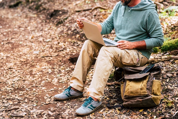 Erwachsener Mann arbeitet mit Computer-Laptop mitten im grünen wilden Wald