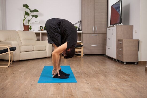 Erwachsener Mann, der beim Training große Zehe-Yoga-Pose macht. Training auf dem Boden.