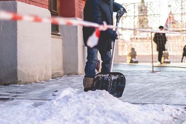 Erwachsener Mann, der Schnee von den Straßen der Stadt schaufelt