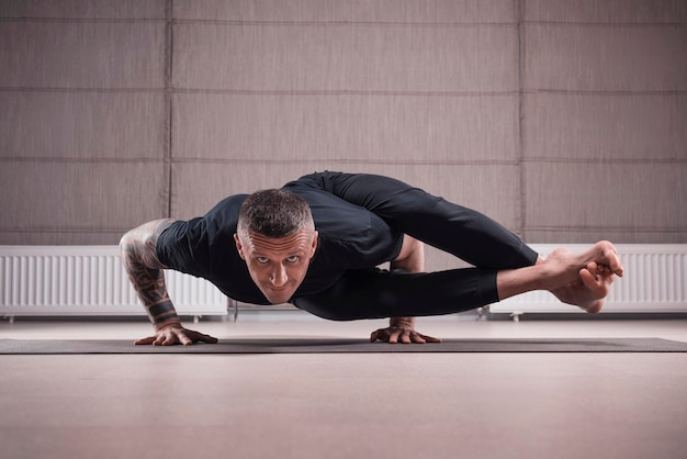Erwachsener Mann führt Asana-Übungen durch. Yoga-Konzept. Sport und gesunder Lebensstil. Gemischte Medien