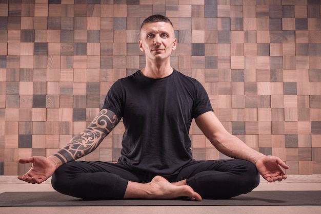 Foto erwachsener mann führt asana-übungen durch. yoga-konzept. sport und gesunder lebensstil. gemischte medien