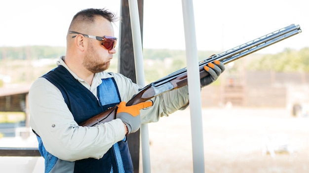 Erwachsener Mann mit Sonnenbrille und Gewehrweste, der das Schießen mit Feuerwaffen übt