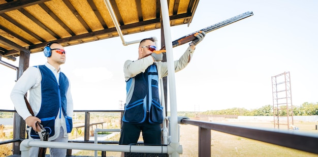 Erwachsener Mann mit Sonnenbrille und Gewehrweste, der das Schießen mit Feuerwaffen übt