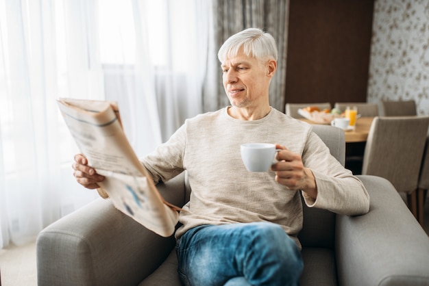 Erwachsener Mann trinkt Kaffee und liest Zeitung