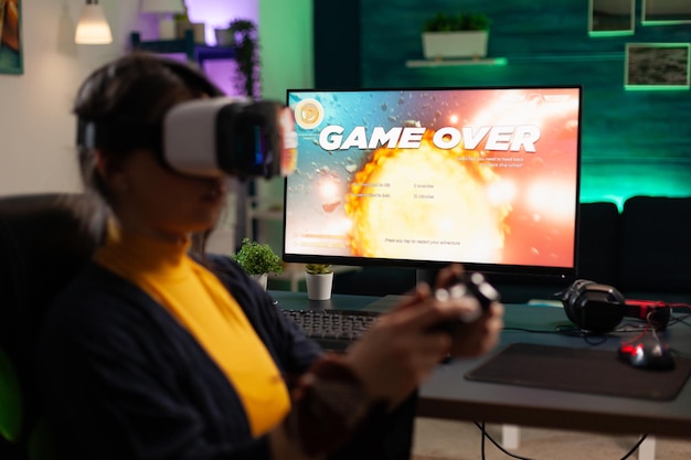 Erwachsener mit VR-Brille verliert Videospiele auf dem Monitor. Frau, die ein Spiel mit Controller und Virtual-Reality-Headset auf dem Computer spielt. Person hat Online-Spiel mit Brille und Joystick verloren.