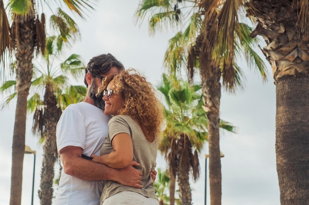 Erwachsenes Paar Mann und Frau genießen Beziehung umarmt mit Glück im Freien in einer Palmenstraße während der Sommerferien Reiseurlaub Freizeitaktivitäten im Freien Menschen in Liebe und Freundschaft lächelnd