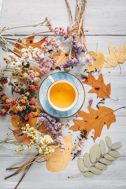 Erwärmungstee des Herbstes auf einem Holztisch mit den Herbstbaumblättern, die in der Nähe liegen