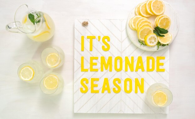 Es el cartel de madera de la temporada de limonada con limones recién cortados en una tabla para cortar madera.
