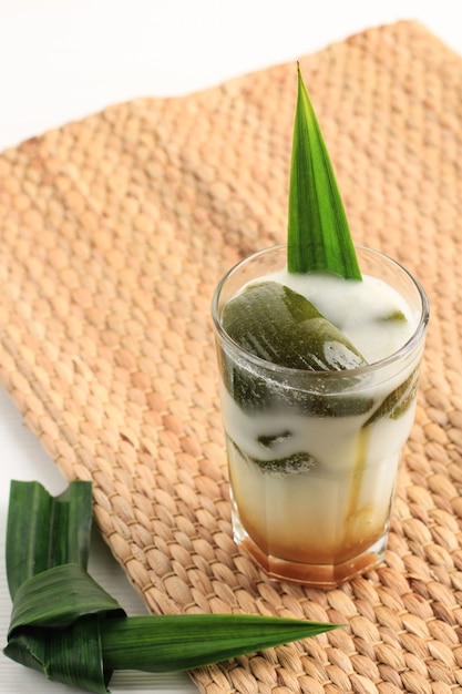 Foto es cincau hijau o gelatina de hierba verde (cincau ijo), postre indonesio hecho de hoja de cincau con leche de coco y azúcar de palma. popular para desayunar durante ramadán. servido en un vaso alto