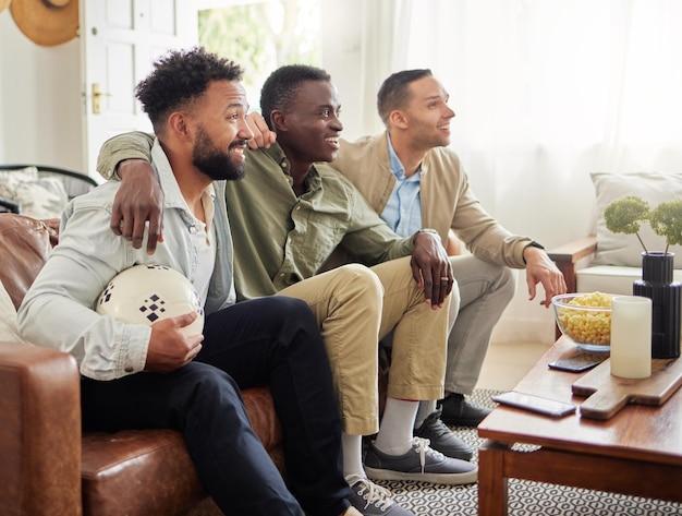 Es el día del juego y solo teníamos que reunirnos para eso. Foto de tres amigos varones viendo algo juntos mientras están sentados en un sofá.