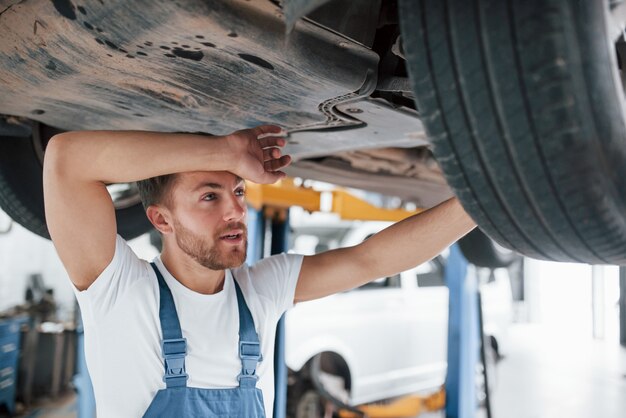 Es dificil. Empleado en el uniforme de color azul trabaja en el salón del automóvil