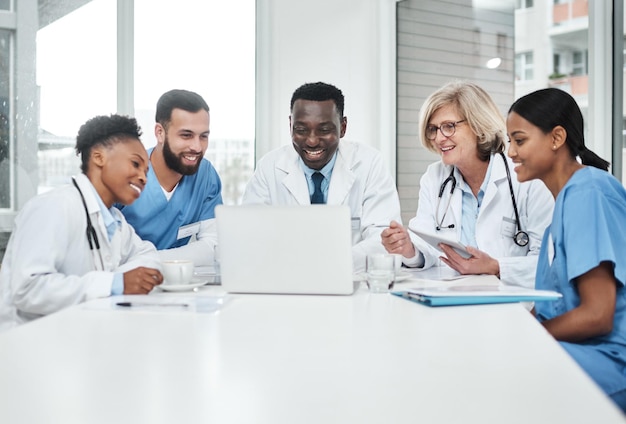 Es dreht sich alles um außergewöhnliche Gesundheitsversorgung Aufnahme einer Gruppe von Ärzten, die während eines Meetings in einem Sitzungssaal eines Krankenhauses einen Laptop benutzen