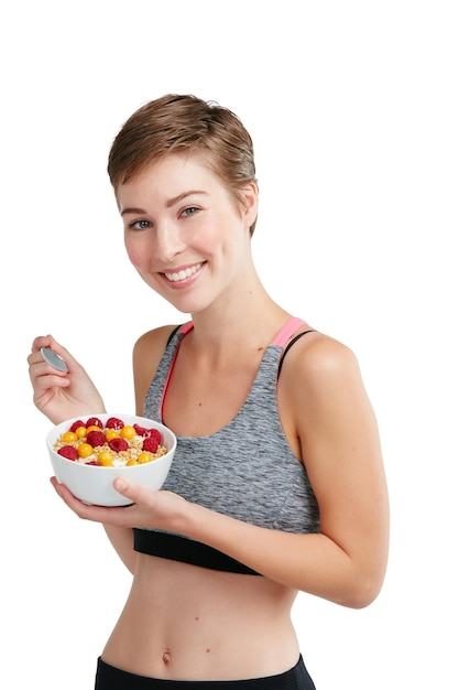 Es geht nicht darum, weniger zu essen, sondern richtig zu essen Studioporträt einer fitten jungen Frau, die eine Schale mit Obst und Müsli vor einem weißen Hintergrund isst